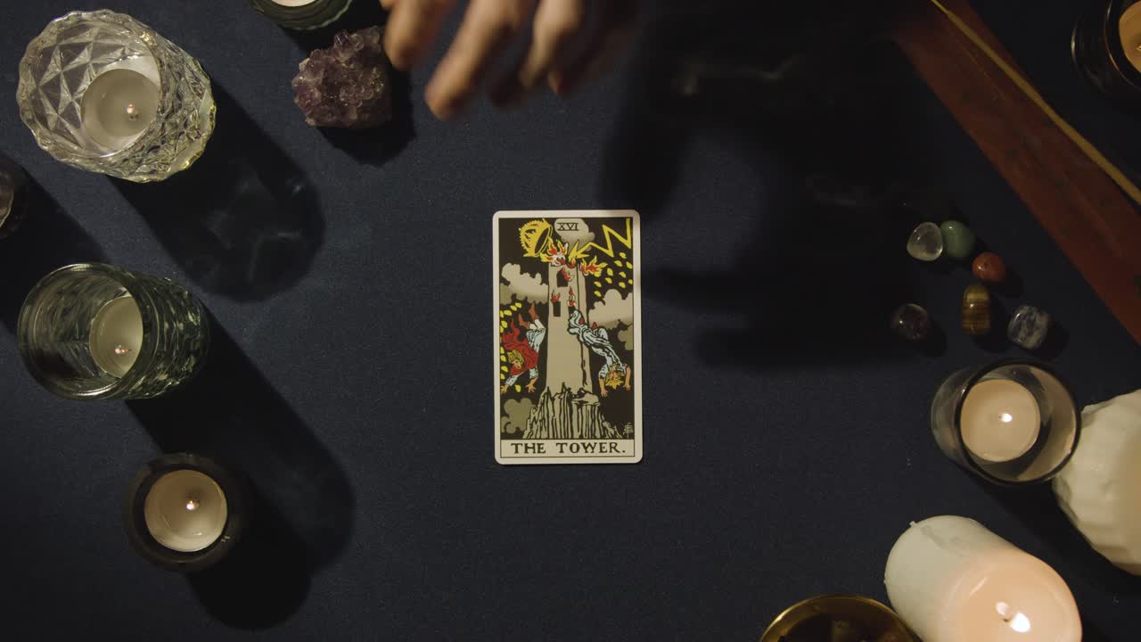 disparo desde arriba de una persona que da lectura de cartas del tarot colocando la carta de la torre en la mesa