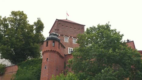 Royal-Wawel-Castle-and-Gothic-Cathedral-in-Krakow,-Poland,-With-Sandomierska-and-Senatorska-Towers,-Polish-Flag-Waving-on-the-Tower