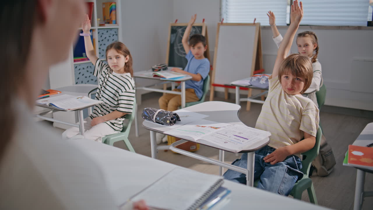 Unknown teacher asking pupils in classroom closeup. Schoolchildren raising hands