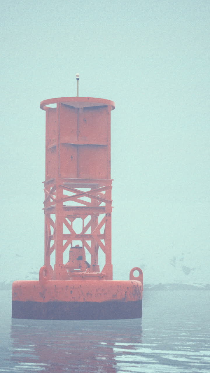 Bright orange buoy stands out in a foggy waterfront setting near a shoreline