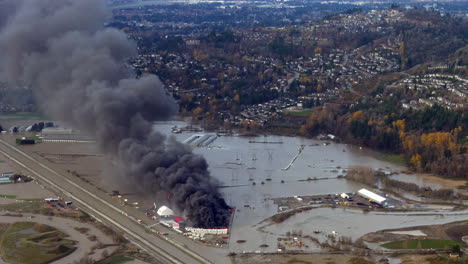 vehículos de caravana rv ardiendo con humo negro contaminado en medio de inundaciones devastadoras en abbotsford, bc, canadá