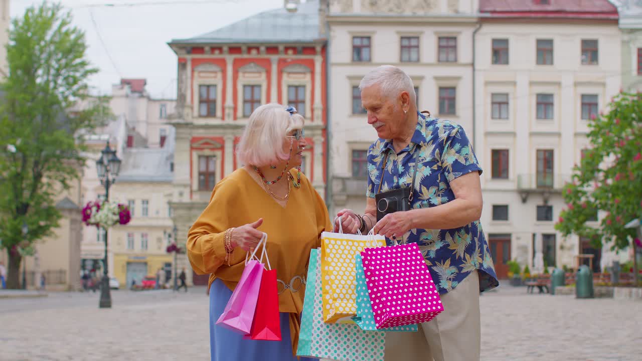 ancianos pareja elegante turistas hombre y mujer caminando con bolsas de colores después de comprar en el centro comercial