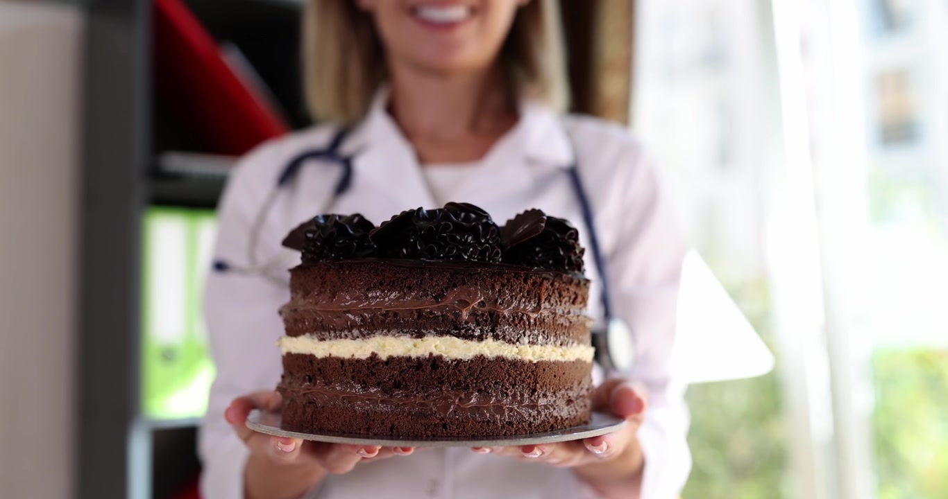 Medico sorridente in camice da laboratorio tiene in mano una torta al cioccolato celebrativa