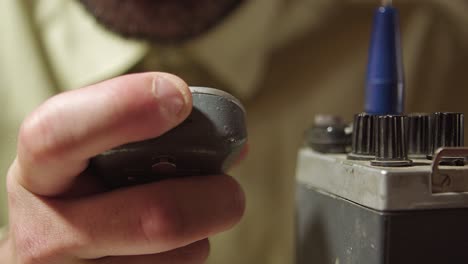 Tuning-old-walkie-talkie,-extreme-closeup-of-finger,-speaking-and-using-it