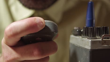 afinando el viejo walkie talkie, un primer plano extremo del dedo, hablando y usándolo