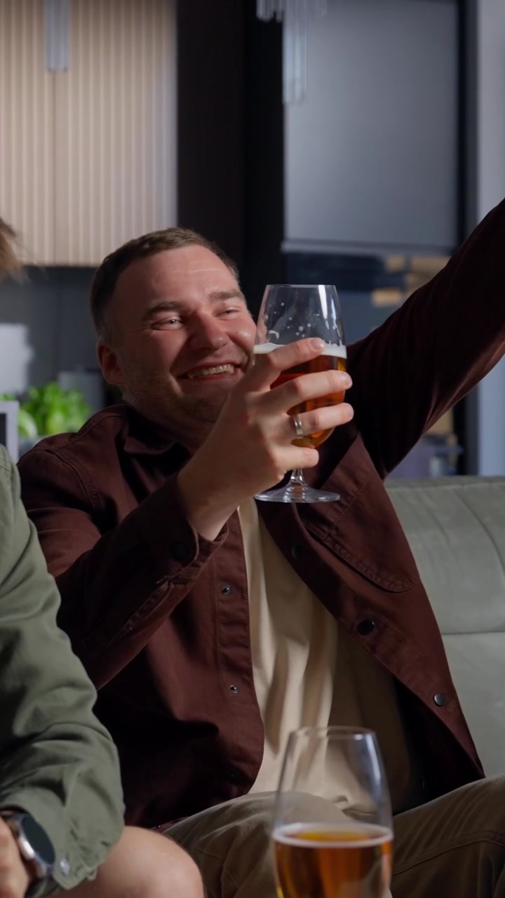 Excited Man Cheers While Watching TV and Drinking Beer at Home
