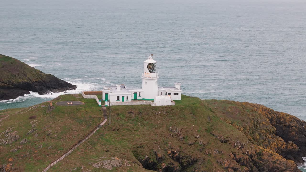 Strumble head lighthouse aerial view orbiting stone tower on Pembrokeshire rugged coastal mainland