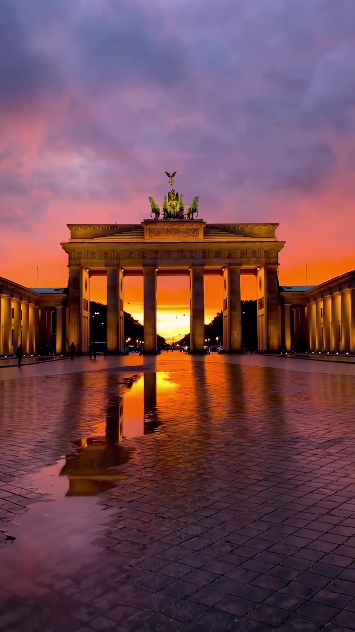 Brandenburger Tor i Berlin ved solnedgang med reflekterende vandpyt