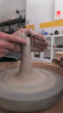 manos moldeando arcilla en una rueda de cerámica