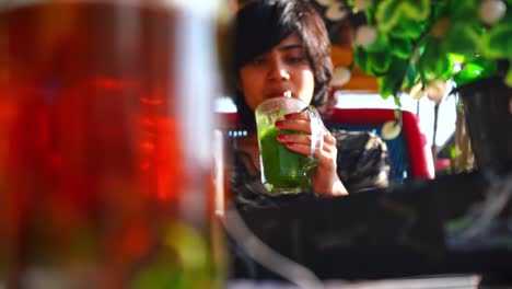 indian girl in a restaurant sipping healthy vegan smoothie in pushkar, rajasthan,  india. slider right, reveal shot