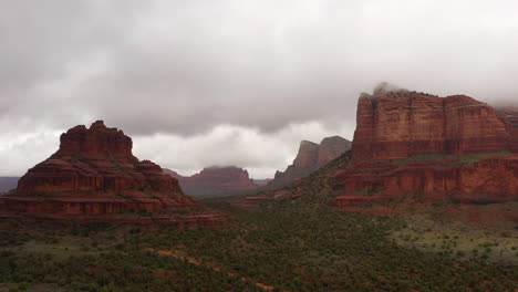 landscape view of red rock formations with thick white clouds on the peak in sedona, arizona, usa - aerial drone shot