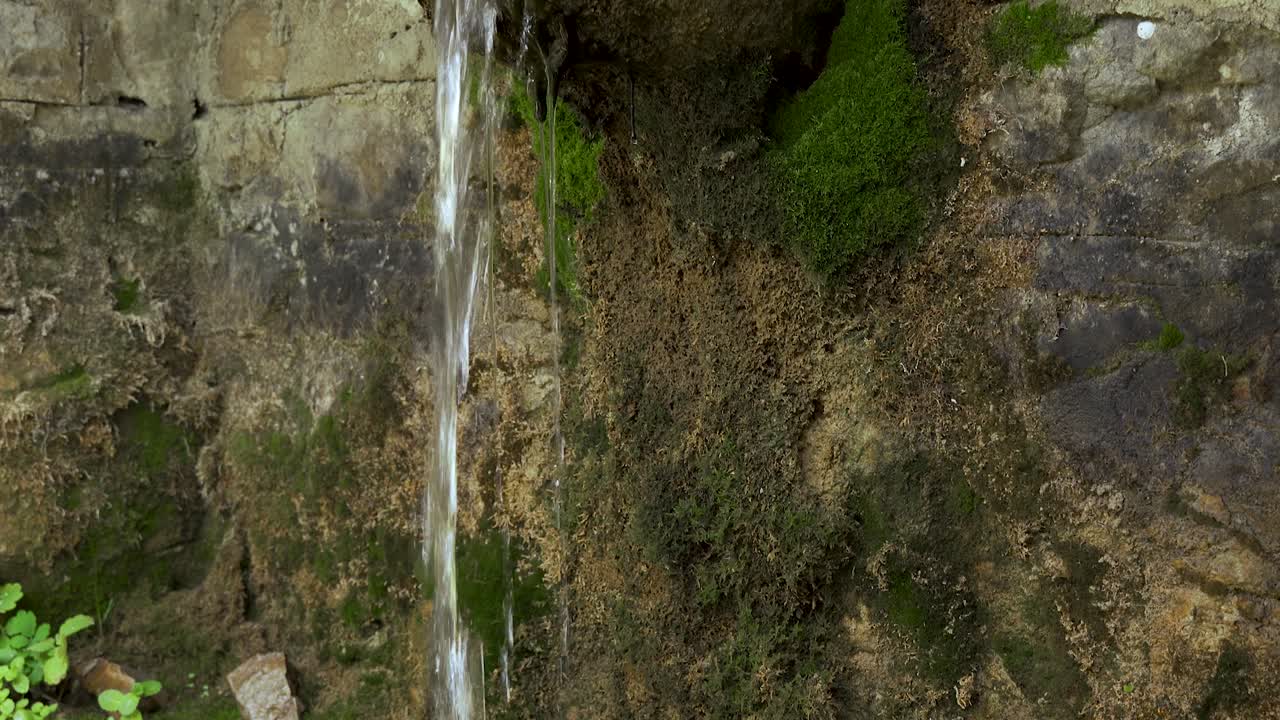 fuente de agua que cae de piedra antigua tallada cubierta de musgo en el pueblo de montaña de dardha en albania