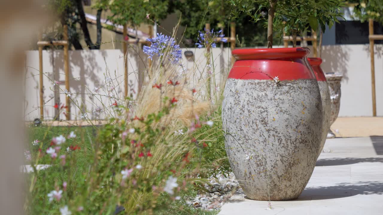 Slow revealing shot of large plant pots with beautiful flowers at a villa
