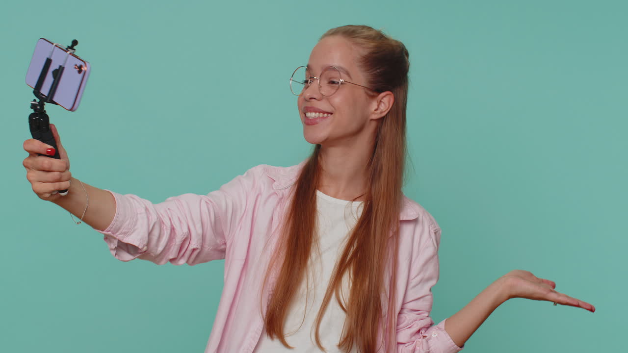 Ragazza viaggiatrice e blogger che si scatta un selfie con il telefono e un bastone da selfie, comunicando tramite videochiamata online.