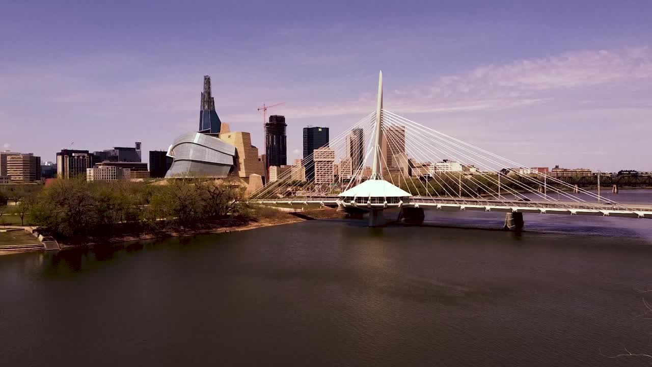 Drone aerial over the Red River showing the Winnipeg Manitoba skyline.