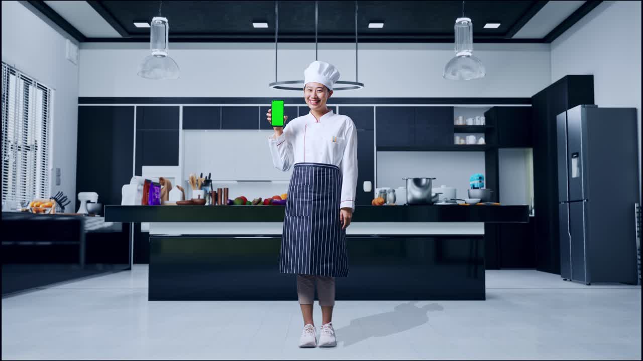 Chef che tiene uno smartphone con schermo verde in una cucina moderna