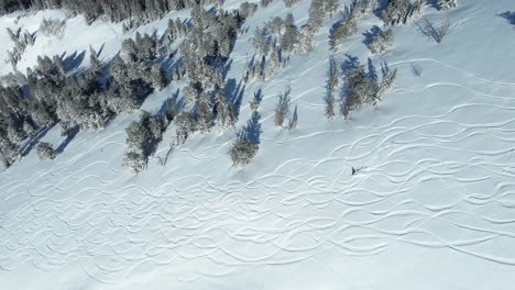 Tiro-De-Drone-De-Snowboarder-Cabalgando-A-Bordo-Por-La-Montaña-Nevada-En-Un-Día-Soleado