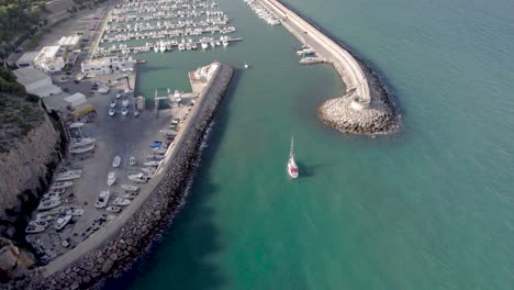 Revelando-Una-Vista-De-Drones-De-4k-Del-Puerto-Náutico-De-Oropesa-Del-Mar-Siguiendo-Un-Pequeño-Velero,-España