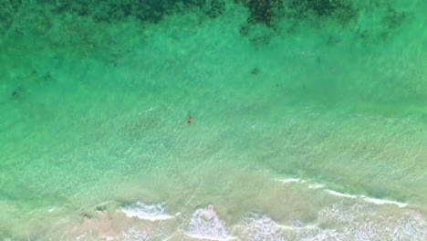 Filmische-Drohnenaufnahme-Im-Abwärts-Gerichteten-Winkel-Eines-Mannes,-Der-Sich-In-Klarem-Ozeanwasser-In-Der-Nähe-Von-Mahahual,-Mexiko,-Entspannt