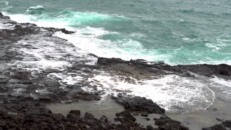 water from pacific ocean shoots out of blowhole along rocky coast of kaui