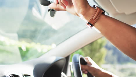 Hands-of-african-american-man-on-steering-wheel-in-car-on-sunny-day,-slow-motion