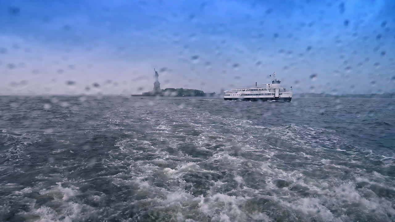 Su damlalarıyla kaplı pencere. New York, ABD'de Özgürlük Heykeli ve başka bir gezi teknesinin tekne penceresinden görünümü. Kasvetli bir günde New York Limanı'nda nehir turu
