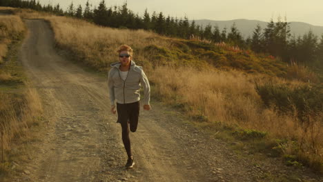 Strong-athlete-jogging-on-dirty-road.-Fit-man-in-sportswear-running-in-mountains