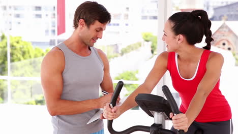 fit woman working out on exercise bike with her trainer