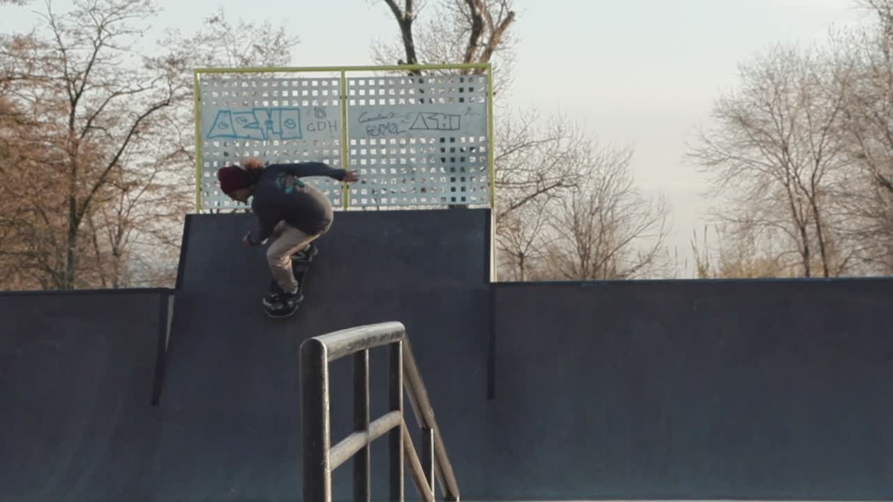 Slowmotion shot of a skateboarder doing a alley-hop Air Indy grab to bank in a skatepark near Barcelona with the sunset light