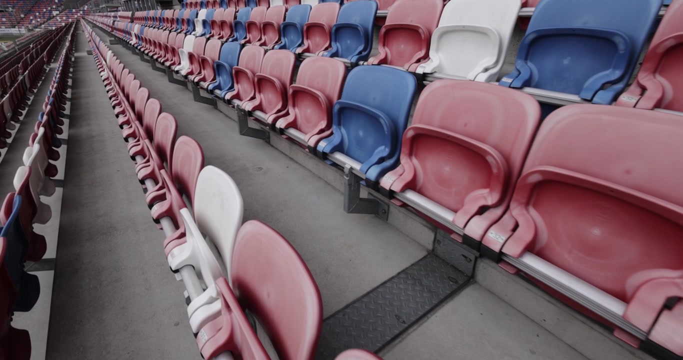 Gradas vacías en un moderno estadio de fútbol del Górnik Zabrze con asientos rojos, azules y blancos en Polonia, toma dinámica en 4K.