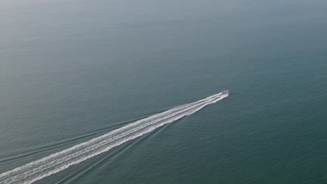 isolated speedboat leaves white wake trail over blue and calm sea water