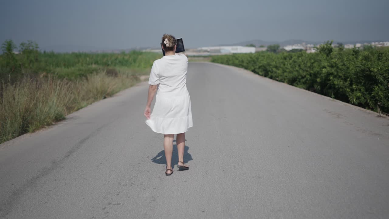 Woman Walking on a Country Road Taking Photos with Tablet