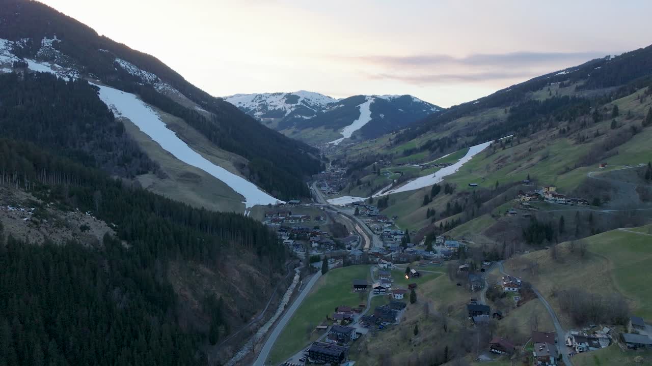 la estación de esquí de saalbach-hinterglemm en austria durante el crepúsculo, inclinándose hacia abajo sobre el pueblo, vista aérea