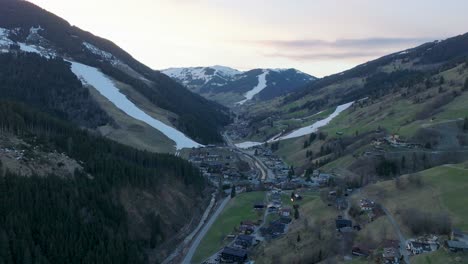 Estación-De-Esquí-De-Saalbach-hinterglemm-En-Austria-Durante-El-Crepúsculo,-Inclinándose-Hacia-Abajo-Sobre-El-Pueblo,-Vista-Aérea