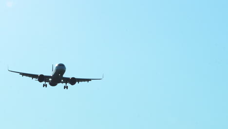 A-commercial-airplane-approaching-for-landing-against-a-clear-blue-sky,-shot-from-a-low-angle