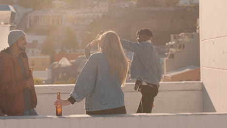 Eine-Gruppe-Verschiedener-Freunde,-Die-Gemeinsam-Rumtanzen-Und-Bei-Sonnenuntergang-Eine-Party-Auf-Dem-Dach-Genießen,-Alkohol-Trinken-Und-Sich-Bei-Einer-Wochenendfeier-Amüsieren