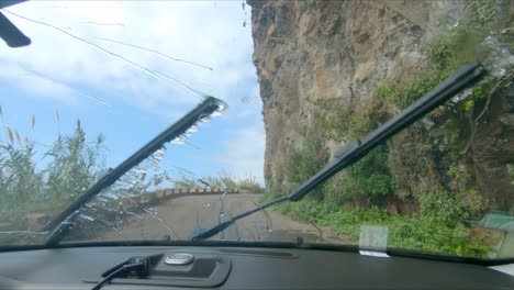 un camión conduce bajo la cascada de ponta do sol en la costa de la isla de madeira - la cascada cae en una carretera