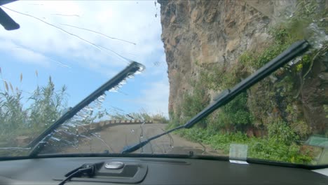 a car drives under ponta do sol waterfall on the coast of madeira island - waterfall falls on a road