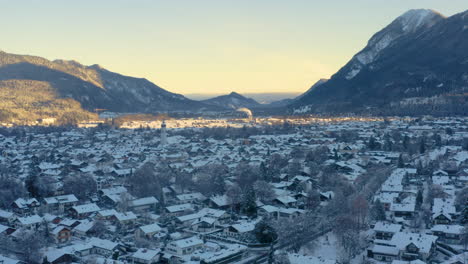 snowy garmisch-partenkirchen town in shadow of mountains, drone shot