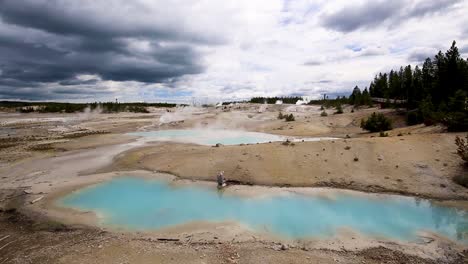 stunning view of geothermal geysers and hot springs with steam clouds rising and turquoise ponds on a cloudy overcast day at yellowstone national park, wyoming, usa