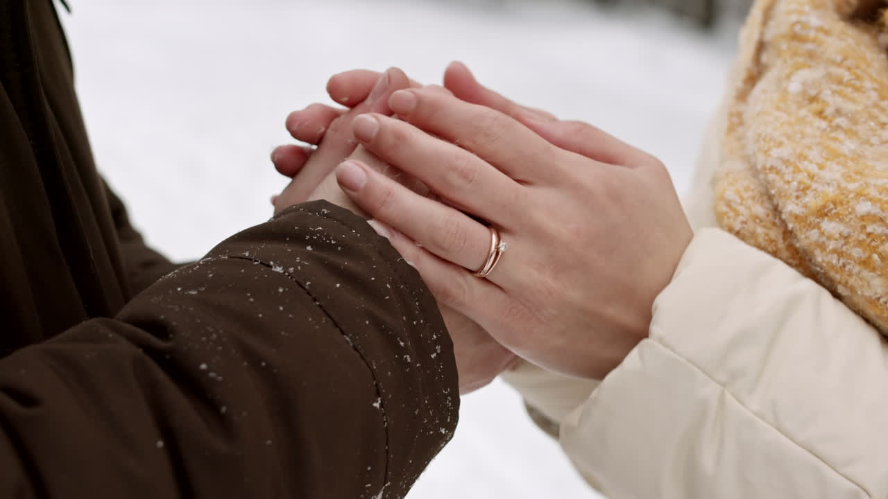 пара держится за руки в снегу