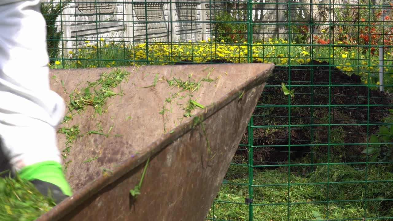 el hombre está tirando hierba cortada a un contenedor de compost en un día soleado