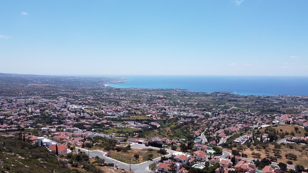 vista aérea panorámica de peya, chipre, con una ciudad extensa, campos exuberantes y el mar mediterráneo bajo un cielo azul claro