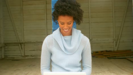 joven mujer afroamericana sentada y usando computadora portátil en la cabaña de la playa 4k
