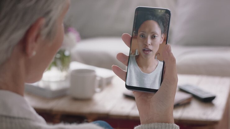 donna matura che fa video chat usando lo smartphone chattando con la figlia sullo schermo del cellulare sorridendo godendo della conversazione condividendo lo stile di vita con la famiglia 4k