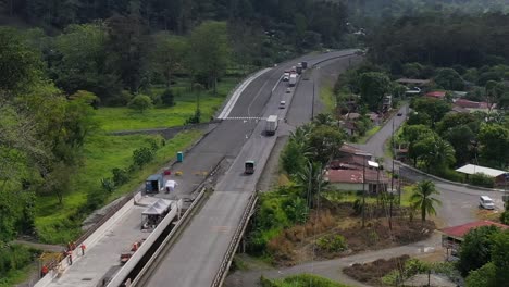 trucks and cars crossing bridge under construction over river affected by drought in san jose, costa rica, aerial pan right reveal shot