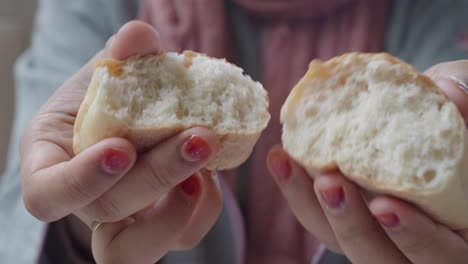 close-up of a woman's hands holding a freshly baked loaf of white bread