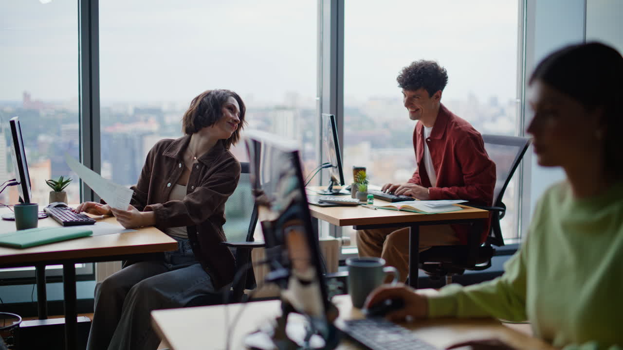 Laughing office employees working open space workplace. Colleagues communicating