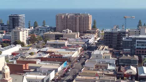 a drone shot looking down on the glenelg beachside precinct near adelaide in south australia. the shot shows jetty road, hotels, the glenelg beach foreshore, and the ocean. great tourism content.