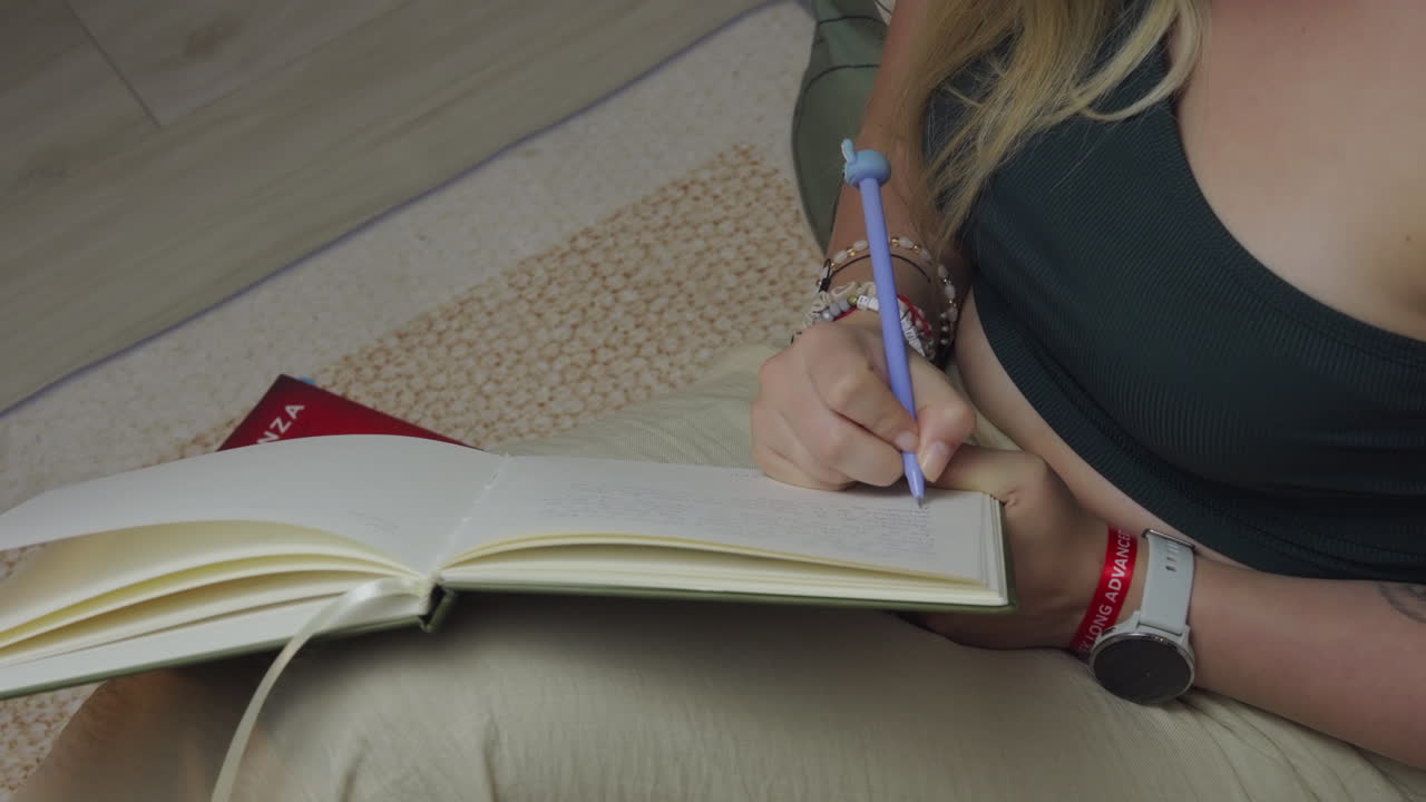 Donna bionda scrive un diario di notte, primo piano in un soggiorno accogliente, slow motion